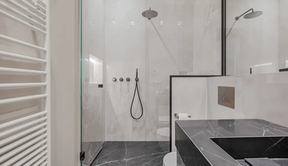 Modern luxury bathroom: walk-in shower with black & white marble, designer vanity, towel warmer. Elegant and comfortable.
