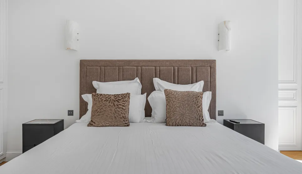 Luxury master bedroom, comfortable double bed with padded headboard, modern and elegant decor. Perfect for a high-end apartment.