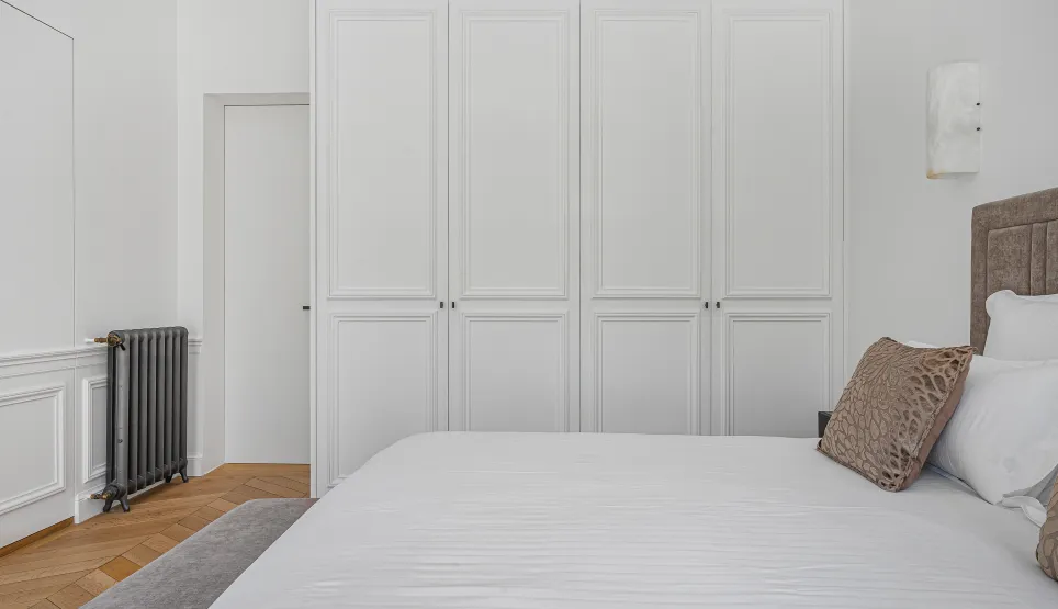 Luxury minimalist bedroom. Built-in wardrobes, comfortable bed, parquet. Contemporary design, elegance & serenity for a master suite.