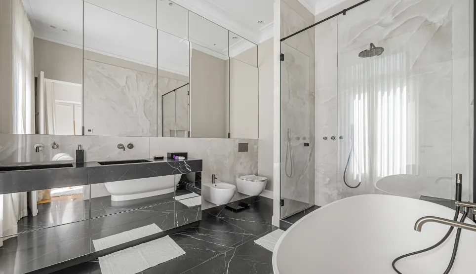 Modern luxury bathroom featuring black and white marble, double vanity, freestanding tub, and walk-in shower. Elegant, high-end design.