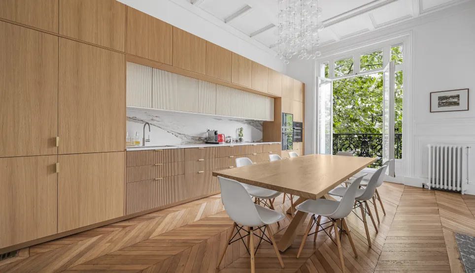 Luxury kitchen dining room, modern elegant design. Parquet flooring, bespoke wood, marble, lush green view. Parisian apartment.