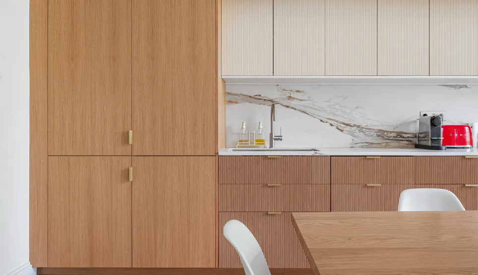 Luxury modern kitchen: light wood, veined marble, gold finishes. Contemporary design with herringbone parquet and Smeg appliance.