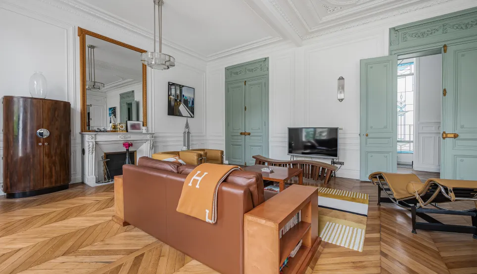 Luxurious Haussmannian apartment, bright living room with chevron parquet, moldings, fireplace & Art Deco design furniture.