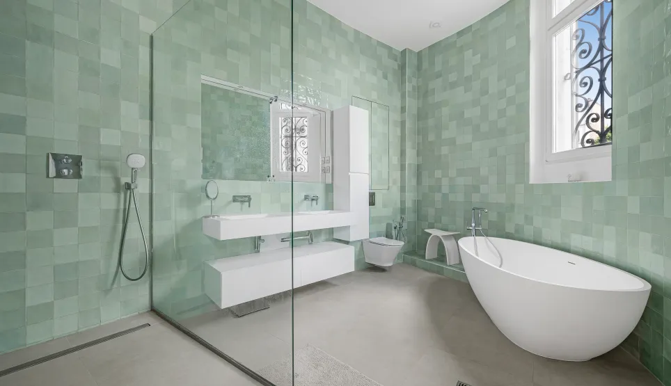 High-end bathroom with sage green zellige tiles, contemporary freestanding bathtub, walk-in shower, and floating double vanity.