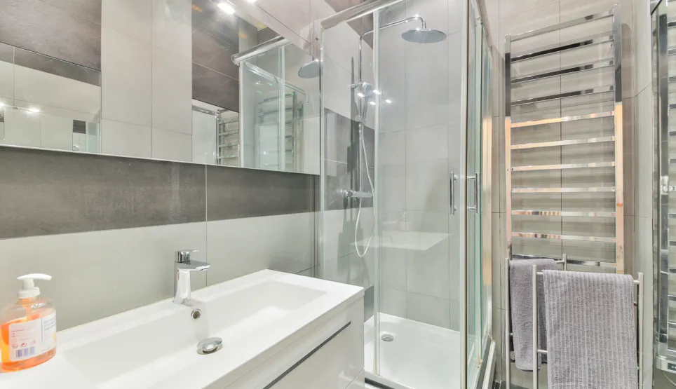 Modern and elegant bathroom with glass shower, designer basin, and chrome towel warmer. High-end finishes for optimal comfort.