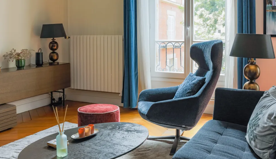 Modern luxury living room: elegant blue designer armchair, comfortable sofa, coffee table, and hardwood floor. Chic, contemporary ambiance.
