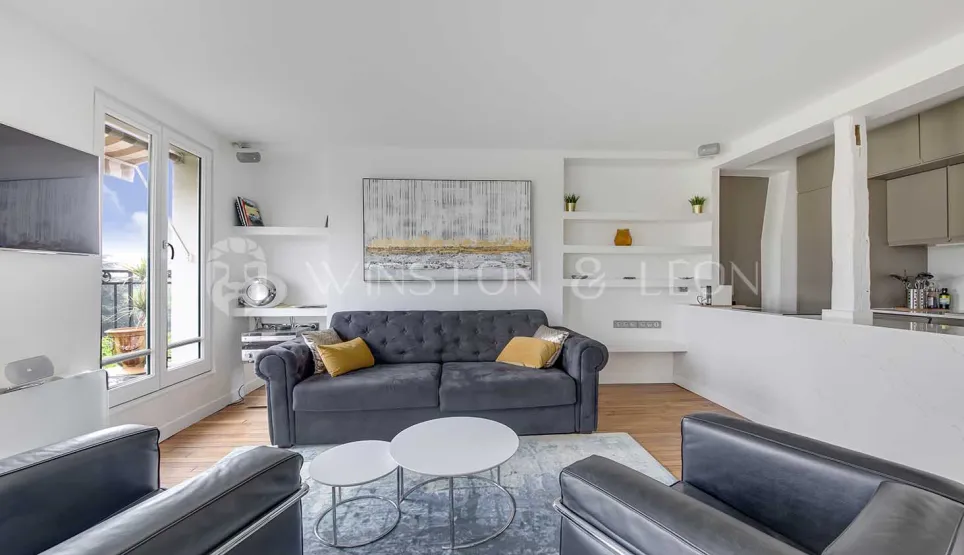 Bright, modern luxury apartment living room with grey sofa, balcony, and open kitchen. Contemporary minimalist design.