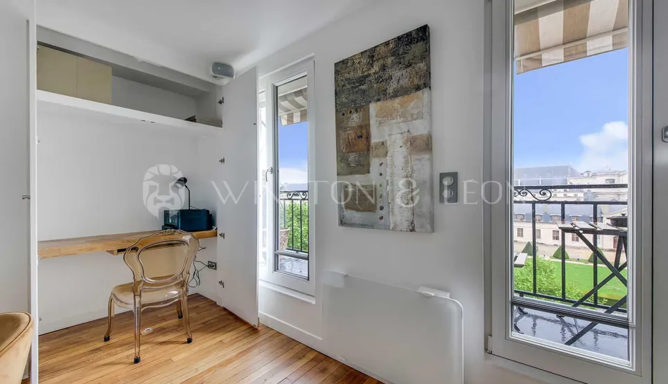 Bright modern office nook with balcony view, hardwood floors. Elegant workspace in a luxury apartment, ideal for a stylish home office setup.