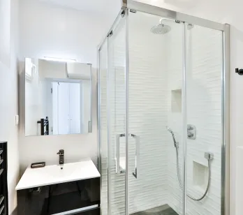 Bright, modern bathroom featuring a walk-in shower, designer vanity, and mirror. Sleek luxury for contemporary apartment living.