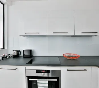 Sleek white modern kitchen with integrated appliances, dark countertop. Perfect for luxury apartment living.