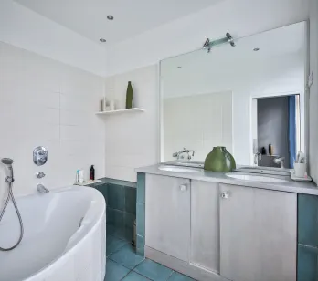 Modern luxury bathroom: bathtub, double vanity, large mirror, white/blue tiles. Sleek design, serene ambiance. Perfect for high-end property.