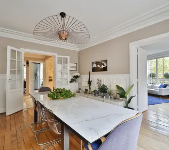Luxury dining room with marble table, designer chandelier & hardwood floors. Bright, elegant & spacious living area, perfect for a high-end apartment.