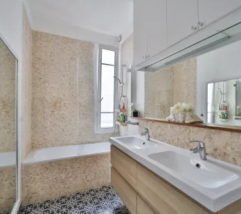 Modern, bright bathroom featuring double vanity, bathtub, elegant tiling, and integrated mirror. Contemporary design for optimal comfort.