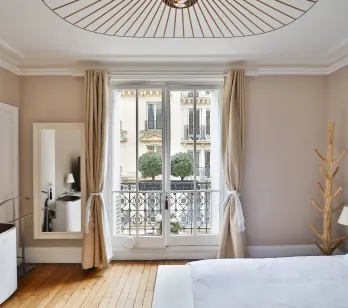 Luxury Parisian bedroom featuring a balcony, hardwood floor, and unique design lighting. Elegant urban retreat.