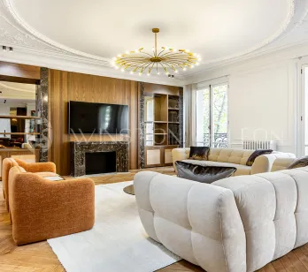 Stunning luxury living room: modern design, marble fireplace, parquet, moldings, designer sofas. Bright and refined ambiance for Parisian apartment.