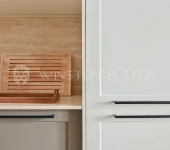 Modern luxury kitchen: light cabinets, black handles, travertine backsplash, wood accents. Elegant and functional design.