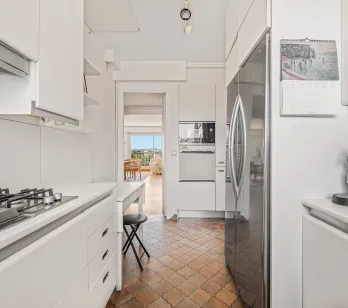 Bright modern kitchen, integrated appliances, unique tiled floor. Open view from living room. Ideal luxury apartment, comfort and style.