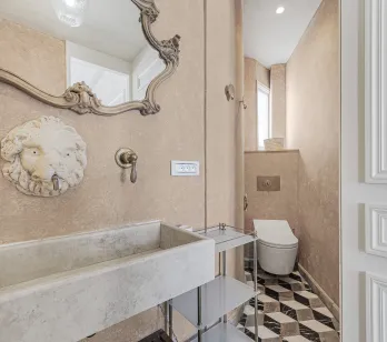 Luxury powder room: ornate baroque mirror, stone sink, lion head faucet. Elegant design, geometric tiles. Chic and refined interior.
