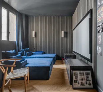 Luxury home cinema: blue velvet seating, large screen, designer walls. Immersive experience for high-end entertainment.