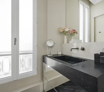 Luxury bathroom featuring black marble vanity and modern design. Elegant, refined ambiance with a bright window.