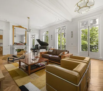 Luxury Parisian Haussmannian living room: grand piano, parquet, mouldings, fireplace, green view. Elegant & bright.