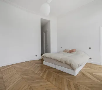 Luxury minimalist bedroom, chevron parquet, white walls. Parisian elegance, natural light. Ideal Haussmannian apartment.