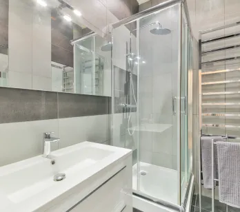 Modern and elegant bathroom with glass shower, designer basin, and chrome towel warmer. High-end finishes for optimal comfort.