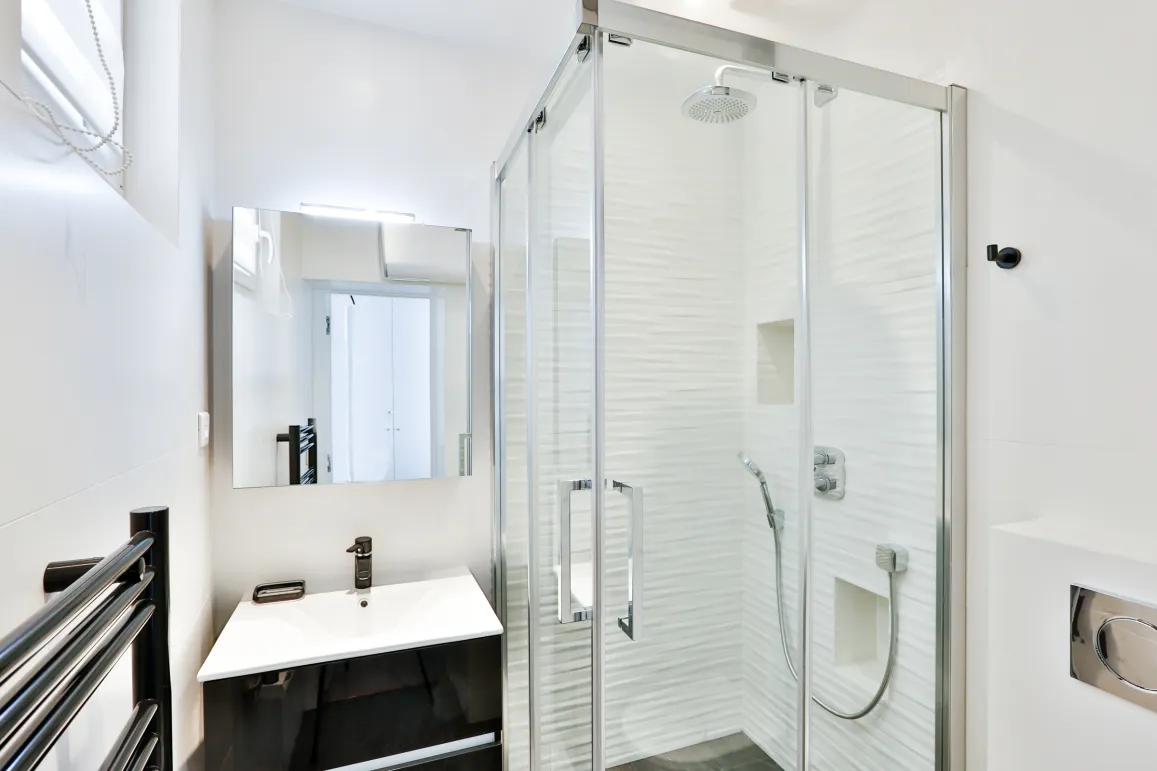 Bright, modern bathroom featuring a walk-in shower, designer vanity, and mirror. Sleek luxury for contemporary apartment living.