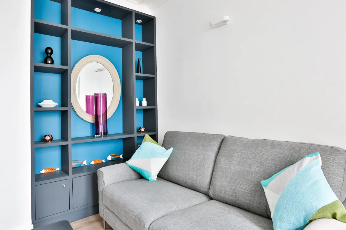 Bright modern living room with grey sofa, custom blue/grey shelving. Chic contemporary decor for a luxury home interior.