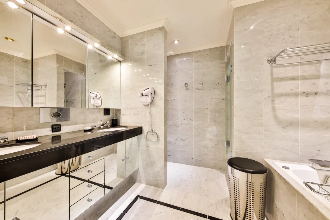 Luxury marble bathroom. Double vanity, illuminated mirror, shower, and bathtub. Modern and elegant design.