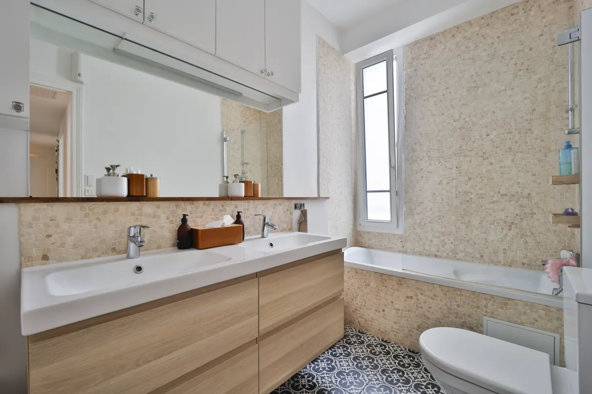 Modern luxury bathroom with light wood double vanity, bathtub, elegant tiles. Bright design, perfect for a high-end property.