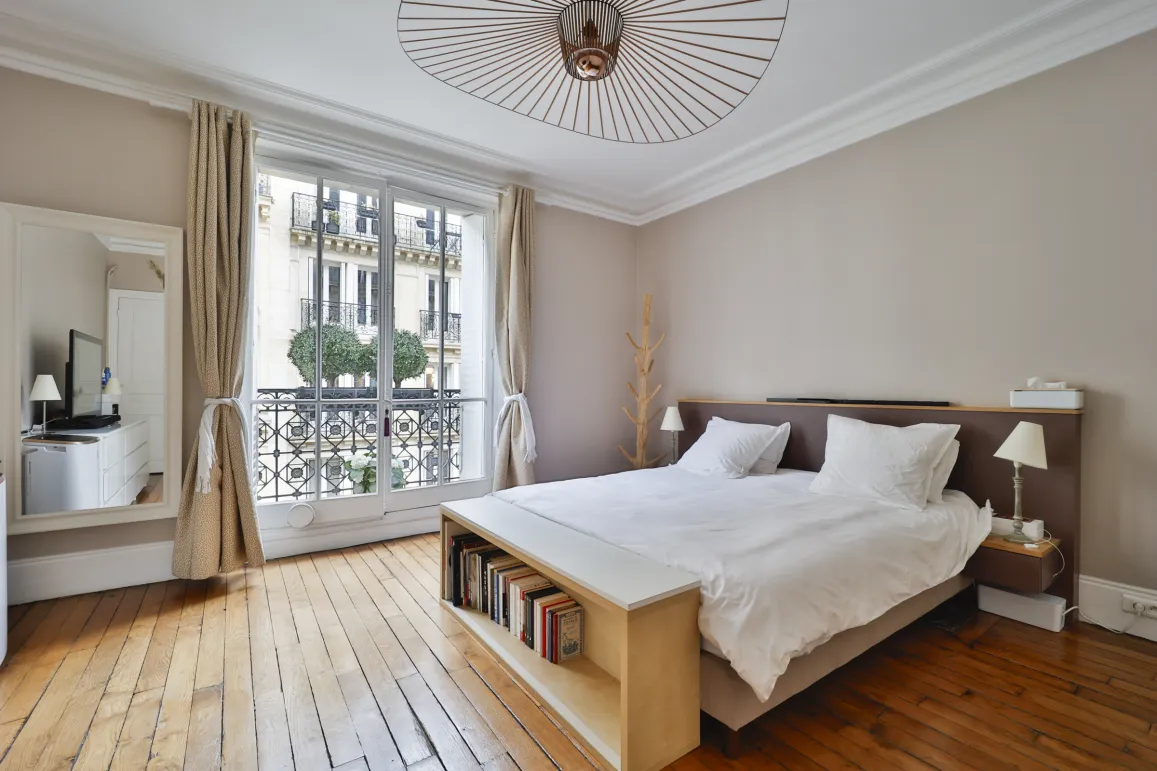 Luxury Parisian bedroom, hardwood floor, Haussmannian balcony view. Modern, minimalist design. Perfect for an exceptional property in Paris.