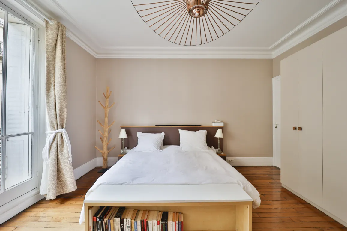 Bright luxury bedroom with hardwood floors, modern and sleek design. Ideal for an elegant and comfortable Parisian apartment.