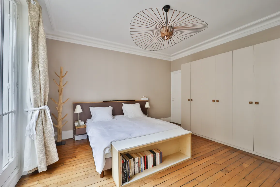 Modern luxury bedroom with comfortable bed, hardwood floors, built-in wardrobe, and designer lighting. Perfect for an elegant apartment.