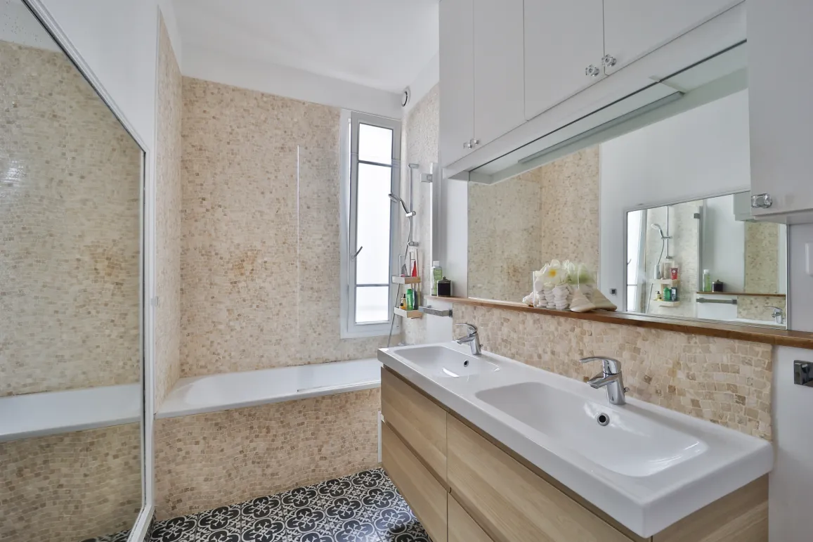 Modern, bright bathroom featuring double vanity, bathtub, elegant tiling, and integrated mirror. Contemporary design for optimal comfort.