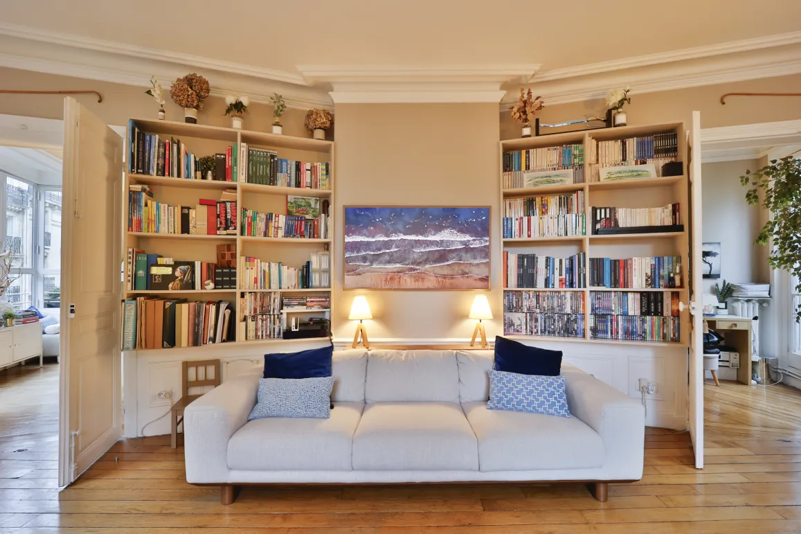 Bright, elegant living room featuring built-in bookshelves, modern sofa, and artwork. The sophistication of a luxury interior.
