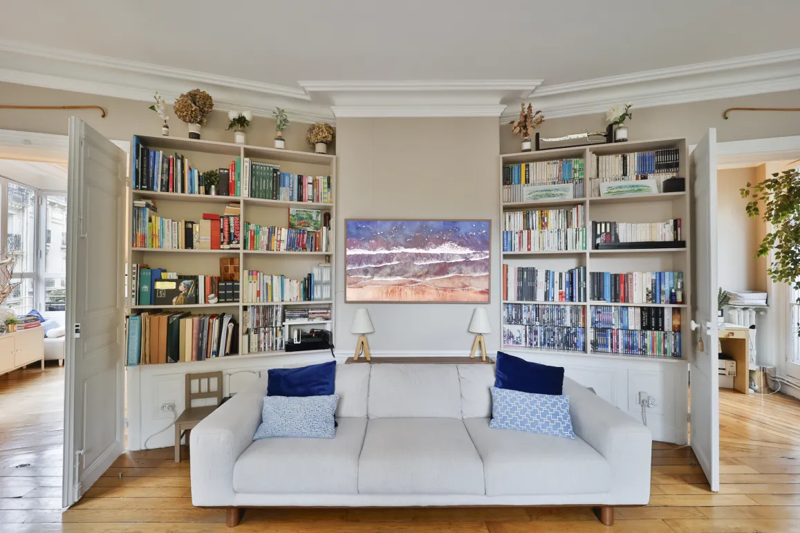 Luxury living room: built-in bookshelves, white sofa, hardwood floor. Elegant & cozy ambiance for exceptional property.