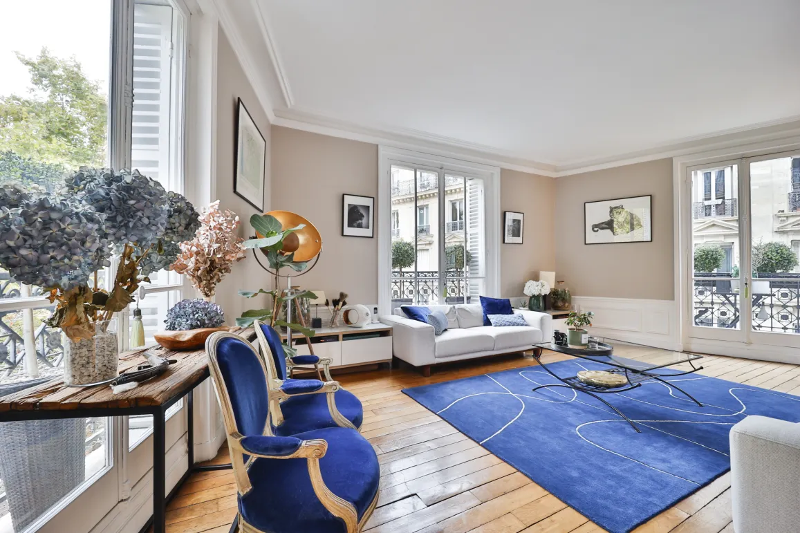 Luxury Parisian Haussmannian living room. Refined design, elegant blue furniture, parquet. Natural light, city view. Prestige apartment.