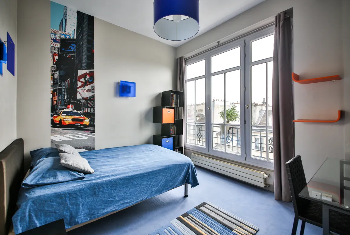 Luxury apartment bedroom: modern, bright, city view. Features a comfortable bed, contemporary design, and urban chic decor with Times Square mural.