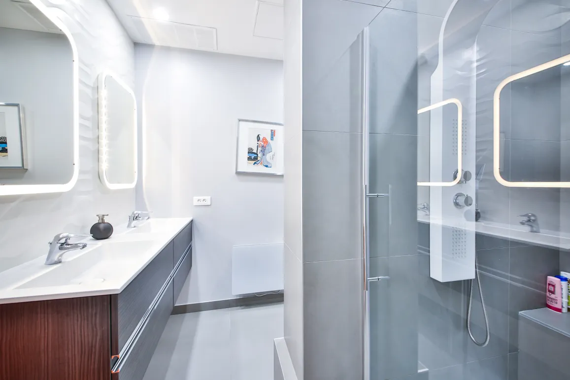 Modern luxury bathroom featuring double vanity, LED mirrors, and glass shower. Sleek design, high-end finishes for an exclusive property.