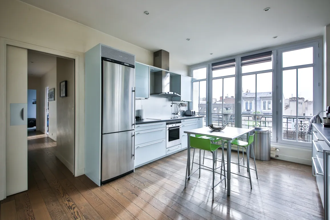 Bright, modern kitchen with stainless steel appliances, hardwood floors. Large bay windows with city views. Luxury apartment, functional design.