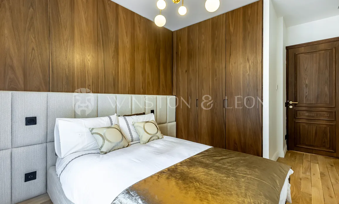 Modern luxury bedroom featuring elegant wood paneling, comfortable bed and padded headboard. Refined design for a master suite.