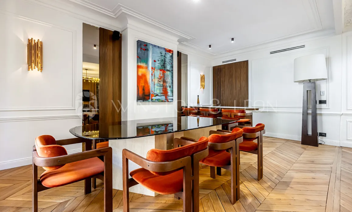 Modern luxury interior: elegant dining room with glass table, orange velvet chairs, contemporary art, and parquet. Refined design.