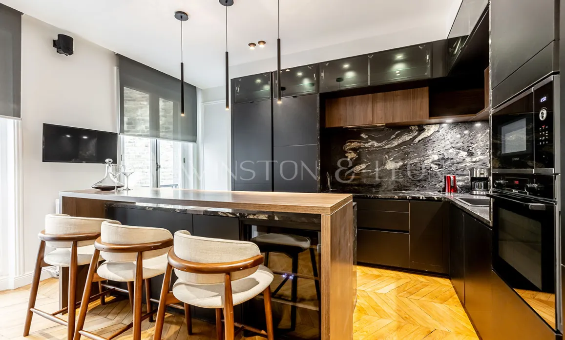 Modern luxury kitchen with wood island, veined black marble, designer stools & pendant lights.