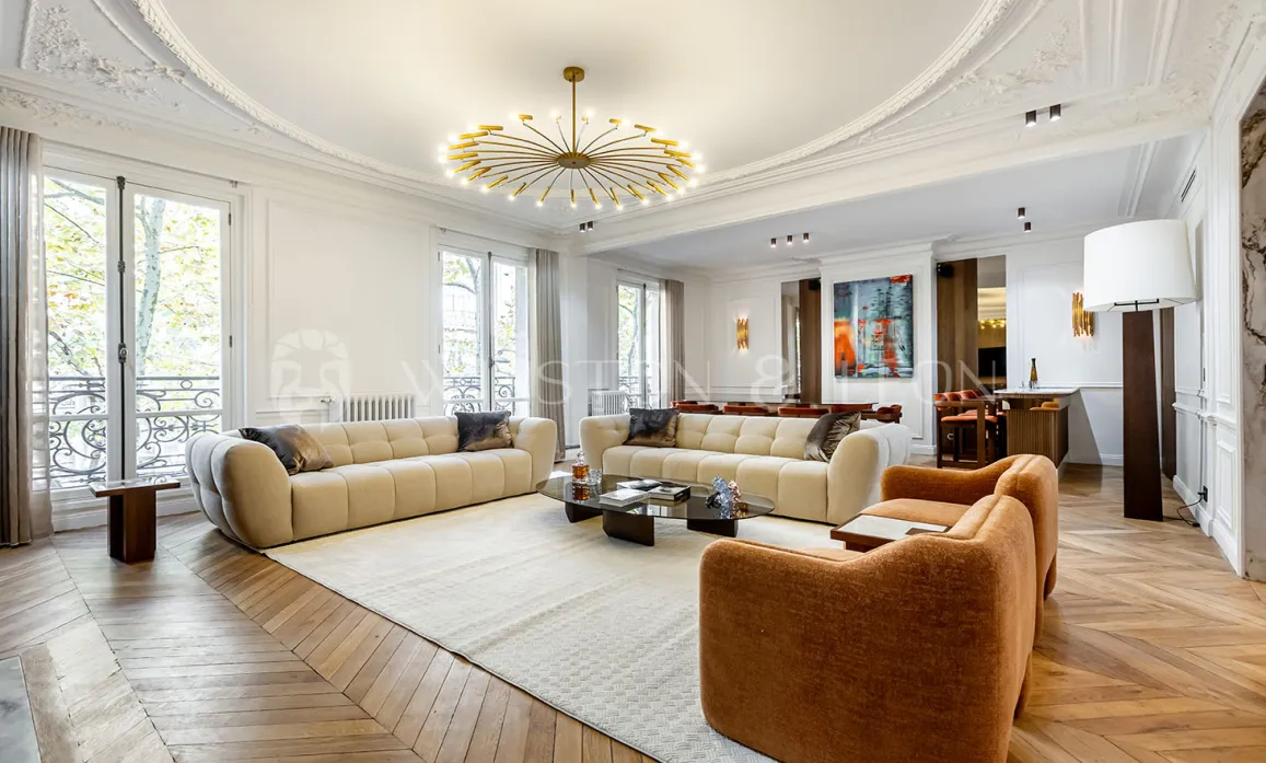 Luxury Haussmannian living room. Contemporary design, herringbone parquet, elegant moldings, and modern chandelier. Prestige apartment.