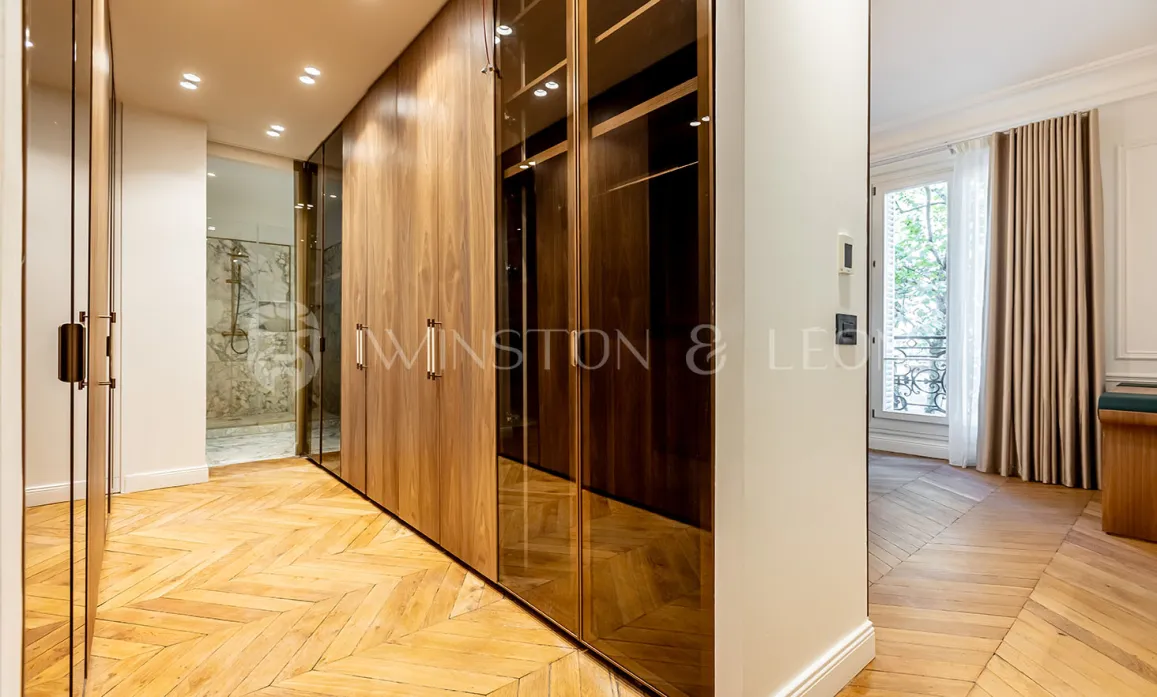 Luxury bespoke dressing room with wood and glass, herringbone parquet. Adjoining bathroom. Elegant design for a prestige apartment.