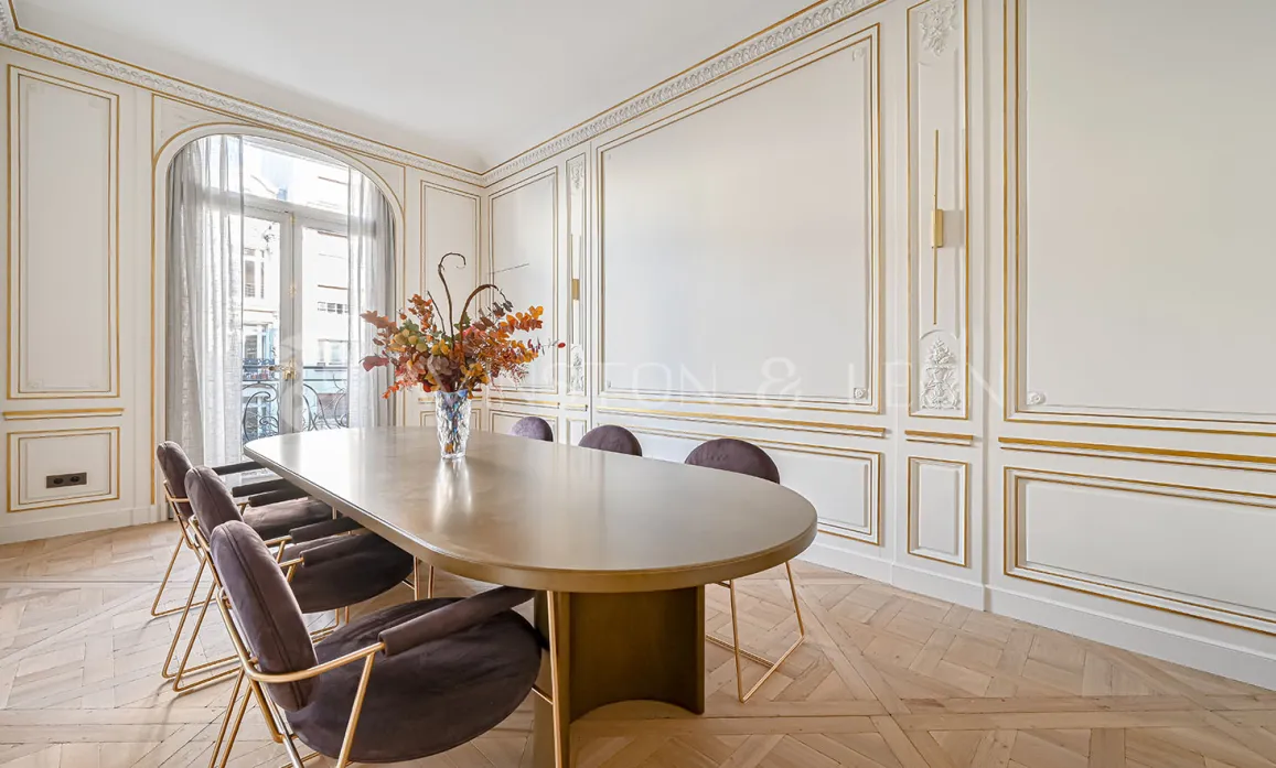 Prestigious Parisian dining room, gold moldings, herringbone parquet, modern furniture. Luxury and refinement.