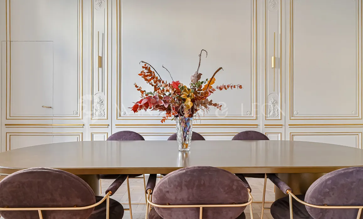 Luxury Haussmannian apartment: elegant dining room. Gold moldings, contemporary velvet chairs & design table. Refined decoration.