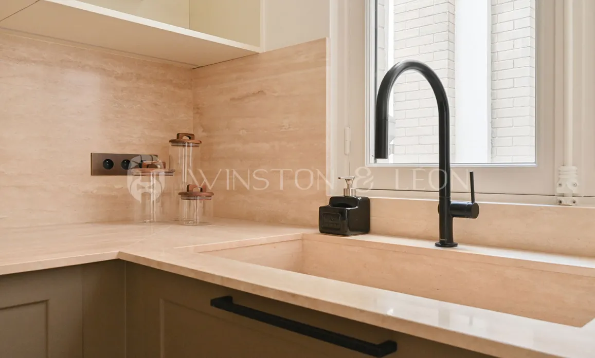 Luxury kitchen: integrated natural stone sink, matte black faucet, elegant countertop. Modern and minimalist ambiance.