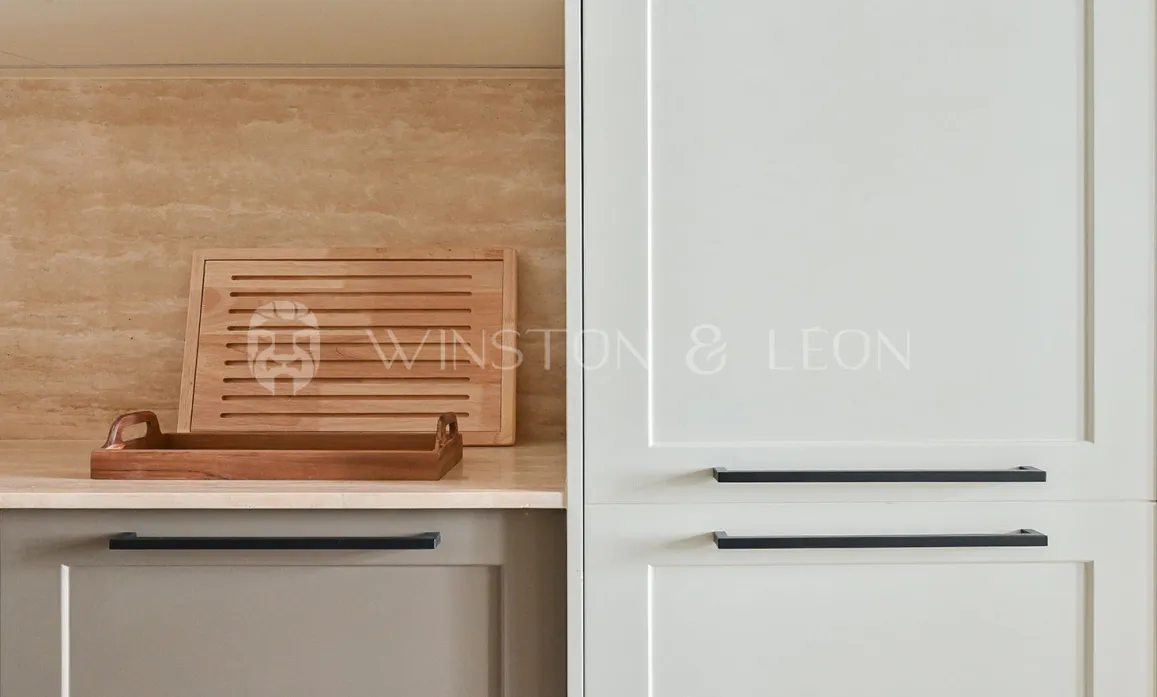 Modern luxury kitchen: light cabinets, black handles, travertine backsplash, wood accents. Elegant and functional design.